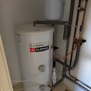 A water heater and pipes in a bathroom.
