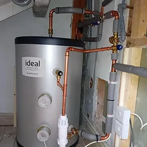 A water heater in a room with exposed pipes.