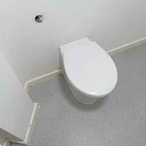 A white toilet sitting in a bathroom next to a wall.