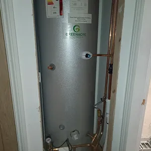 A water heater in a bathroom next to a door.