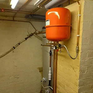 A large orange tank sitting next to a brick wall.